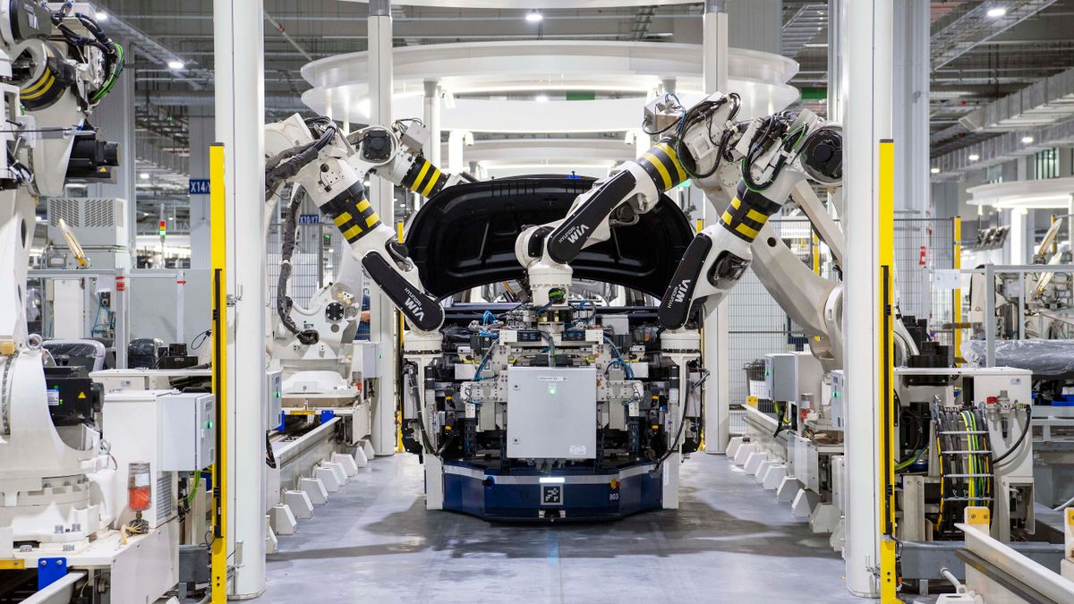 自動車工場で車体を組み立てる複数の産業用ロボットアーム
